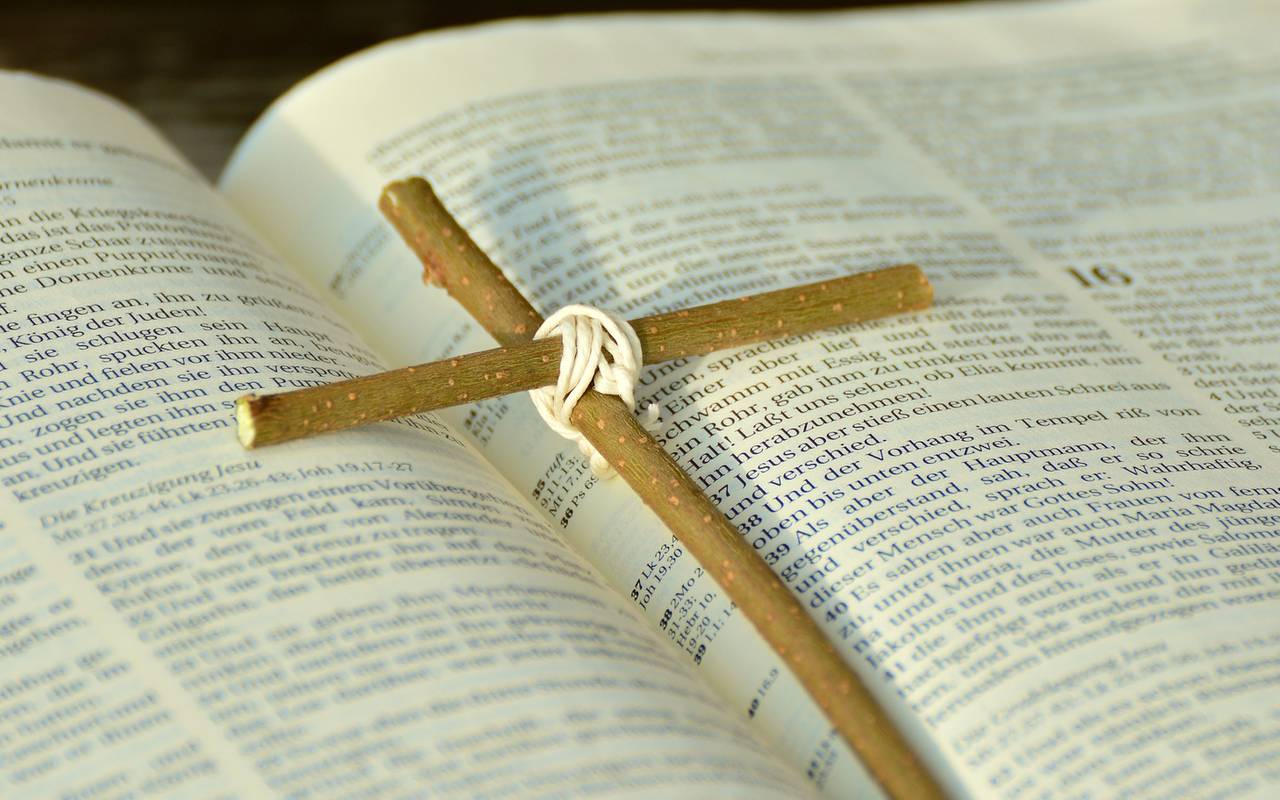Ein schlichtes Holzkreuz liegt auf einer geöffneten Bibel.