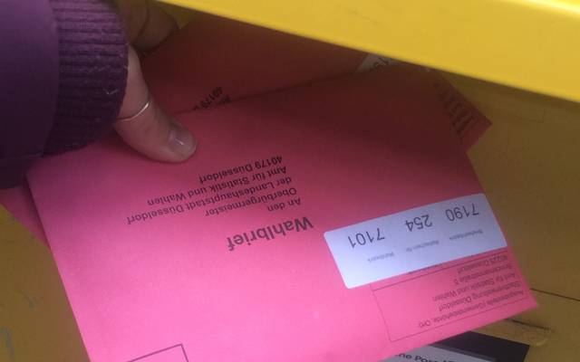 Ein rosa Briefumschlag wird in den Briefwahl gesteckt. Hier wird Briefwahl gemacht.