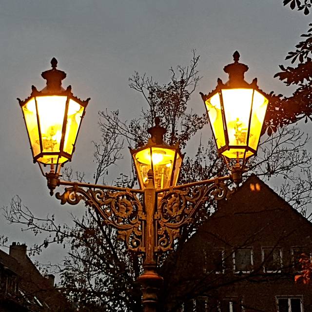 Drei Gaslaternen leuchten in der Dämmerung