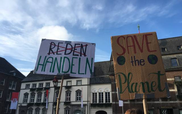 Zwei Demo-Plakate zum Thema Klimaschutz. "Reden" ist durchgestrichen, stattdessen ist "Handeln" zu lesen. "Save the planet" steht auf einem weiteren Plakat.