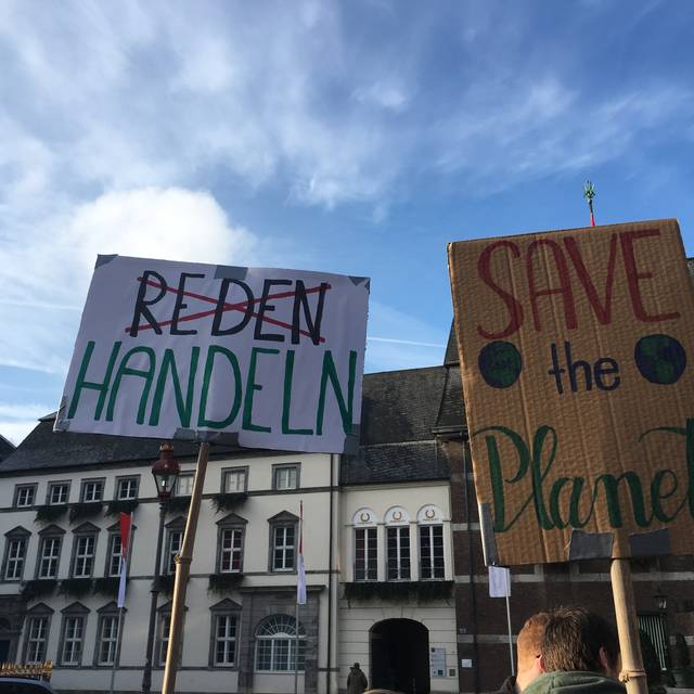 Zwei Demo-Plakate zum Thema Klimaschutz. "Reden" ist durchgestrichen, stattdessen ist "Handeln" zu lesen. "Save the planet" steht auf einem weiteren Plakat.