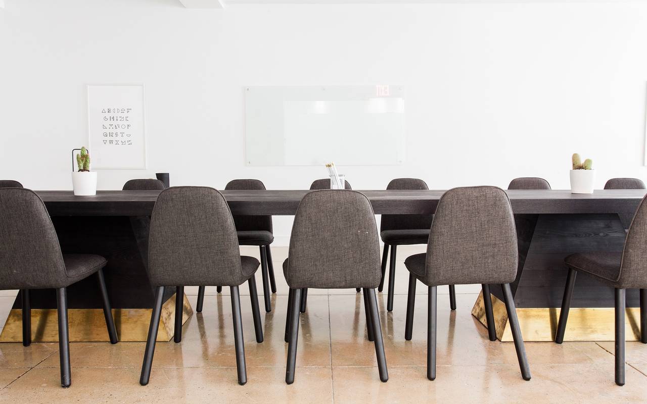 Graue Stühle stehen an einem Konferenztisch in einem leeren Büro.