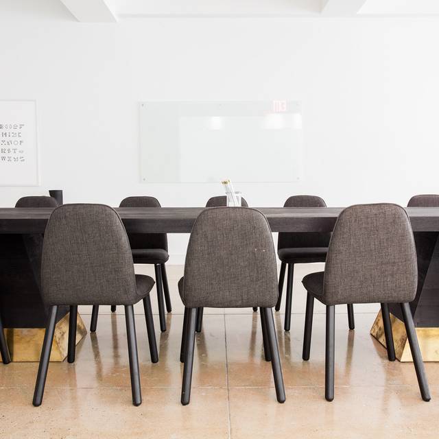 Graue Stühle stehen an einem Konferenztisch in einem leeren Büro.