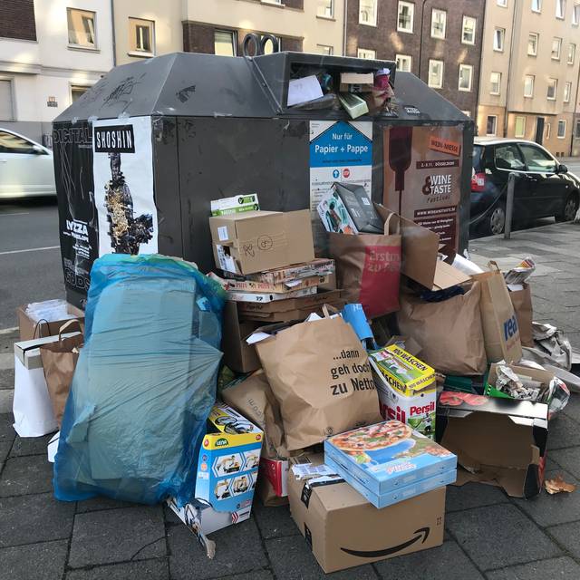 Müll liegt vor einem Müllcontainer.
