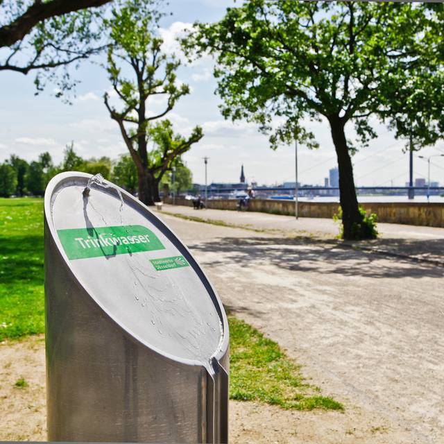 Ein Trinkwasserbrunnen von den Stadtwerken Düsseldorf im Rheinpark in Golzheim. Im Hintergrund ist der Rhein zusehen.