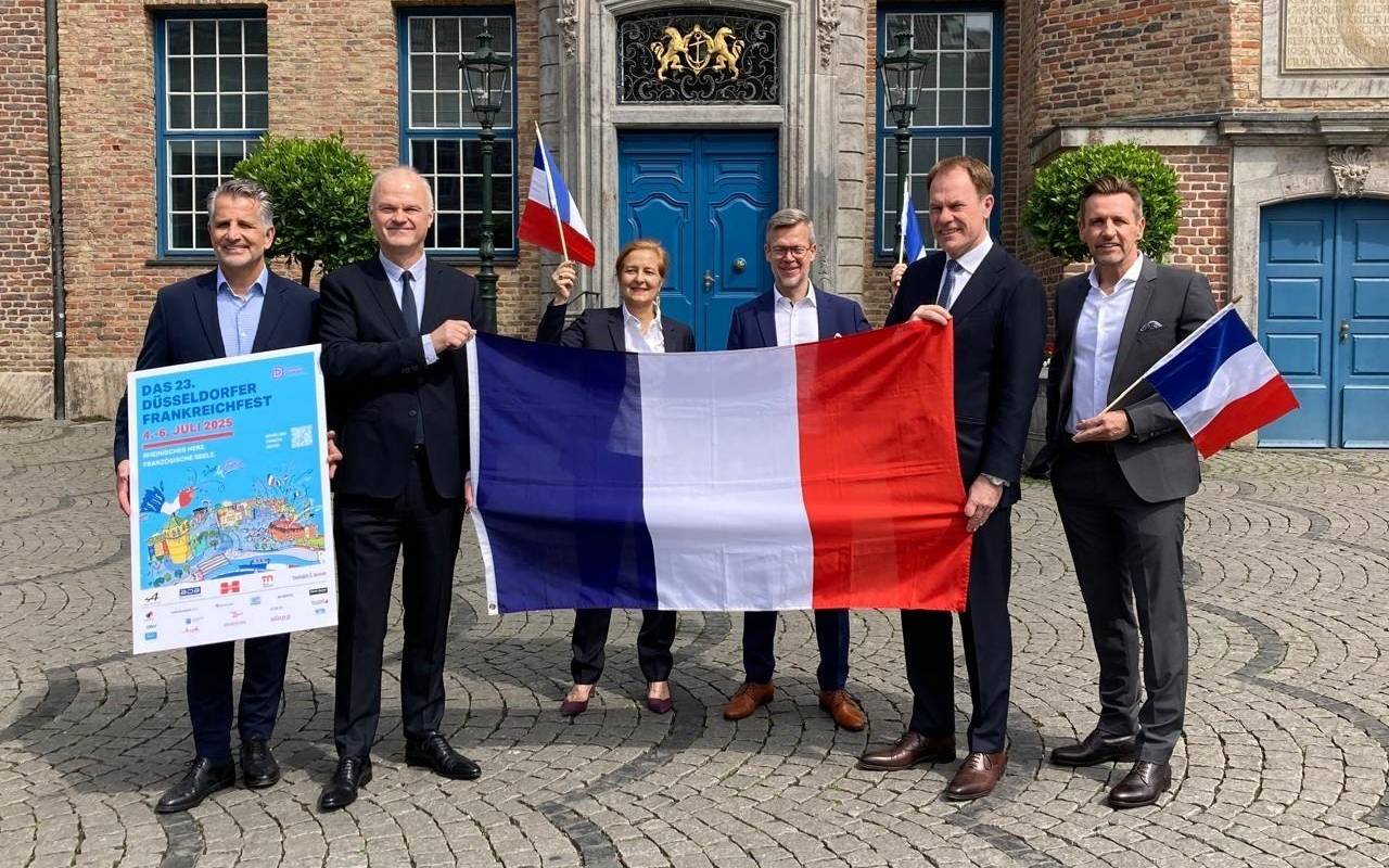 Ein Gruppenfoto vor dem Düsseldorfer Rathaus mit Frankreich-Fahne zum Frankreichfest