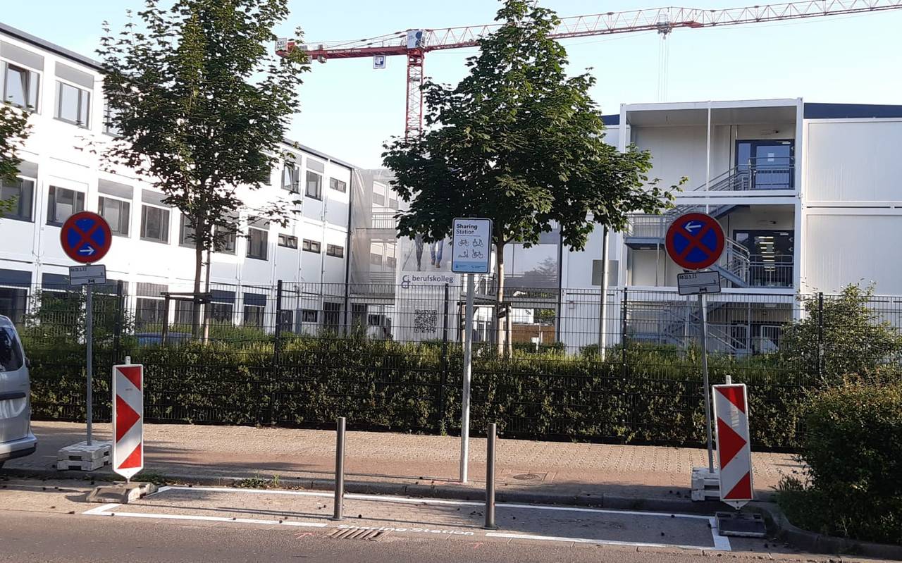 Im Vordergrund ein abgesperrter Parkplatz, an dem ein Schild mit der Info "Sharing-Station"