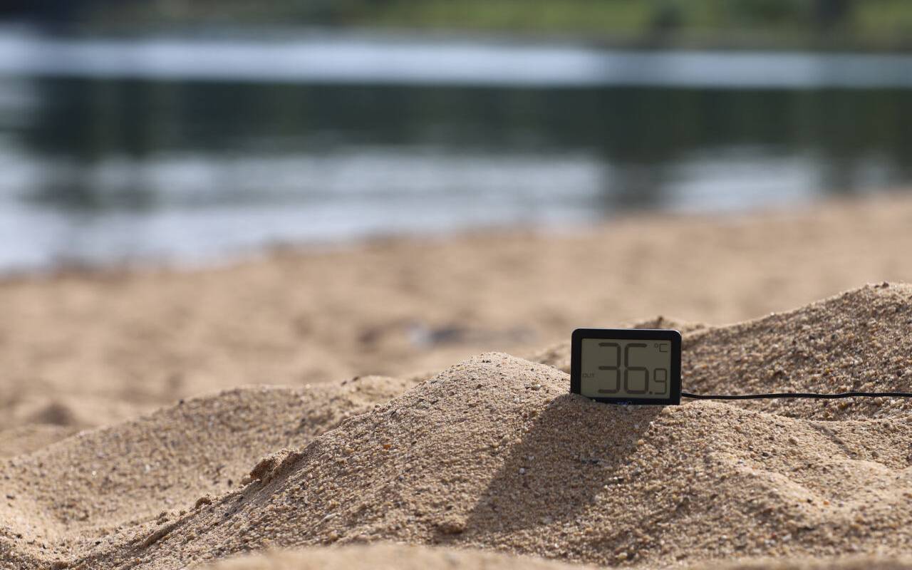 Ein Thermometer zeigt an einem Badestrand knapp 37 Grad an.