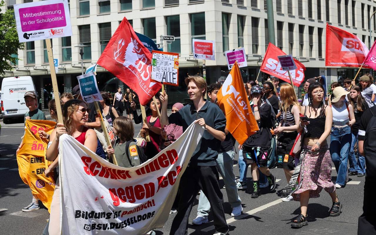 ine Gruppe Schüler*innen demonstriert, sie halten Banner und Schilder hoch und laufen über eine Straße.