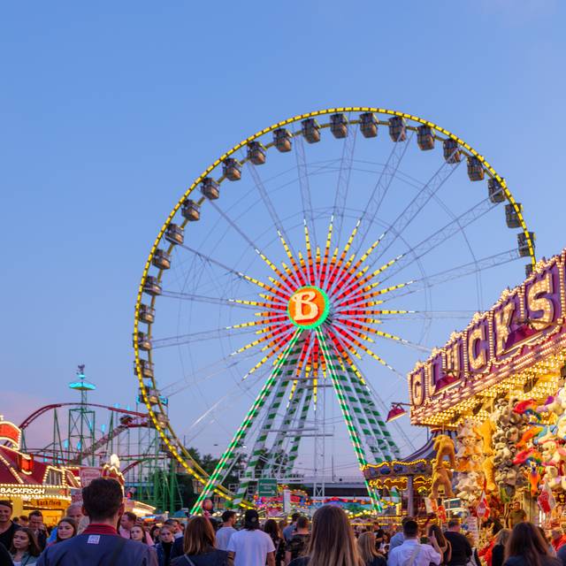 Die Düsseldorfer Rheinkirmes bei Nacht. Mit Riesenrad und dem Glückhaus, einer Losbude.