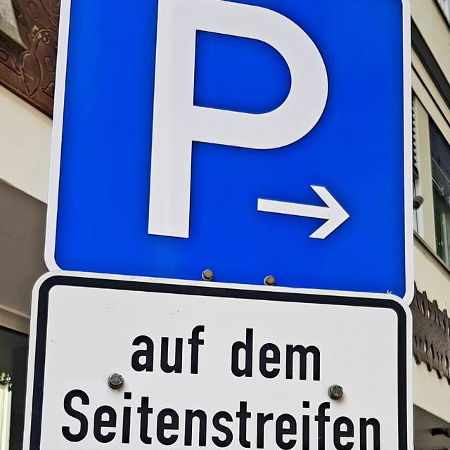 Ein blaues Schild, dass das Parken regelt. In diesem Fall geht um reservierte Plätze für Menschen mit Behinderungen.
