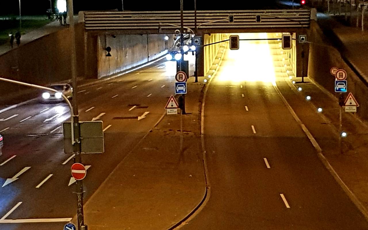 Ein Bild bei Nacht zeigt den Rheinufertunnel. Auf der linken Seite sind Autos und Scheinwerfer zu sehen. Die rechte Röhre des Tunnels ist Autofrei.
