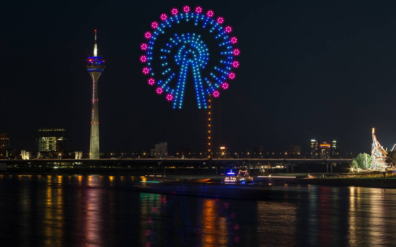Eine Visualiesierung der Drohnenshow zur Rheinkirmes. Drohnen malen ein Risenrad in den Himmel.