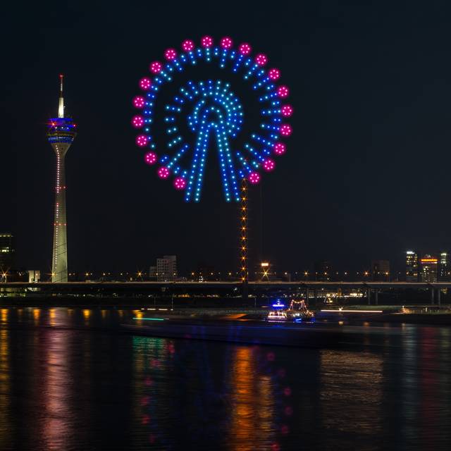 Eine Visualiesierung der Drohnenshow zur Rheinkirmes. Drohnen malen ein Risenrad in den Himmel.