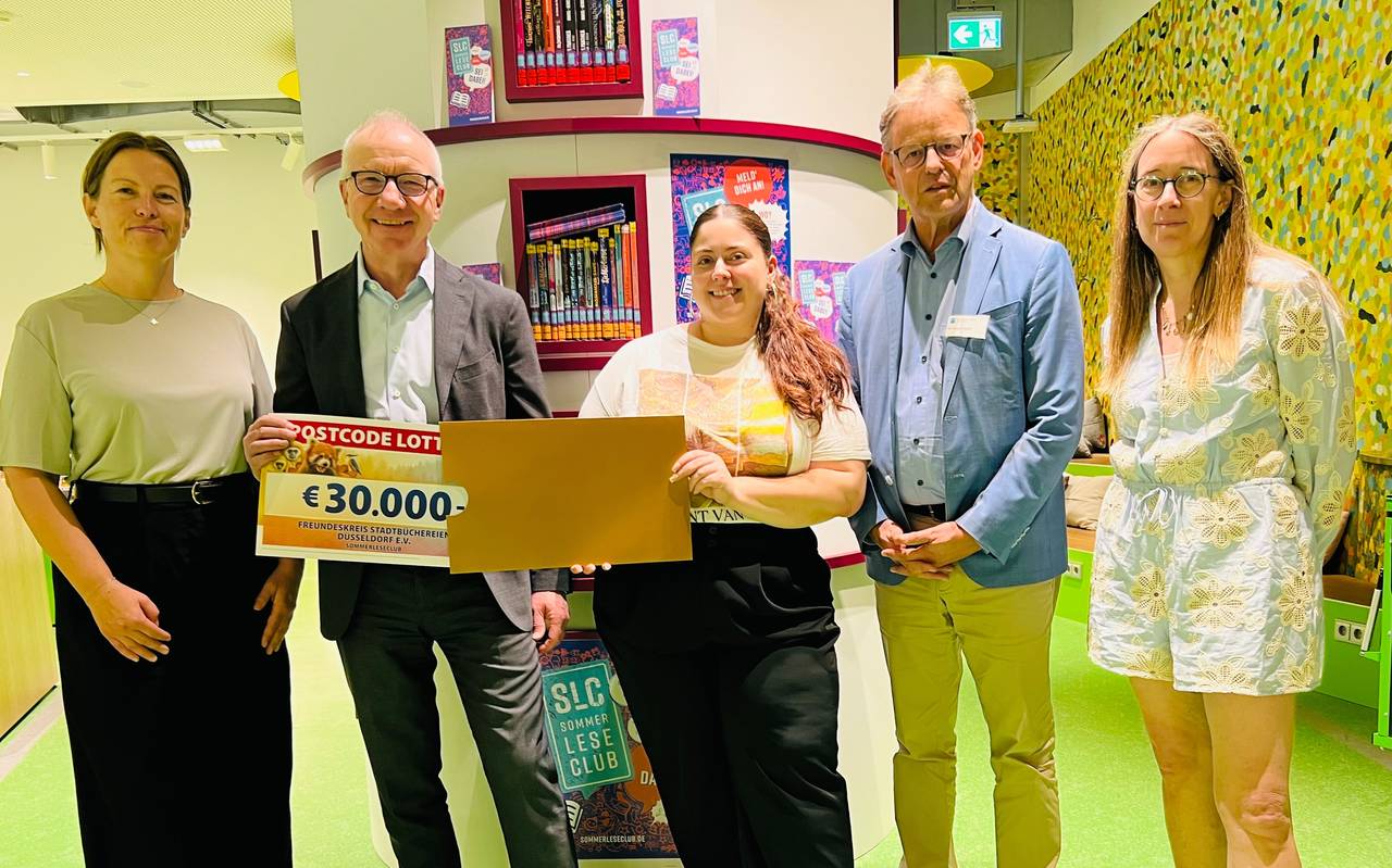 Fünf Menschen stehen in der Stadtbücherei und freuen sich über einen Gutschein über 30.000 Euro der Deutschen Postcode Lotterie