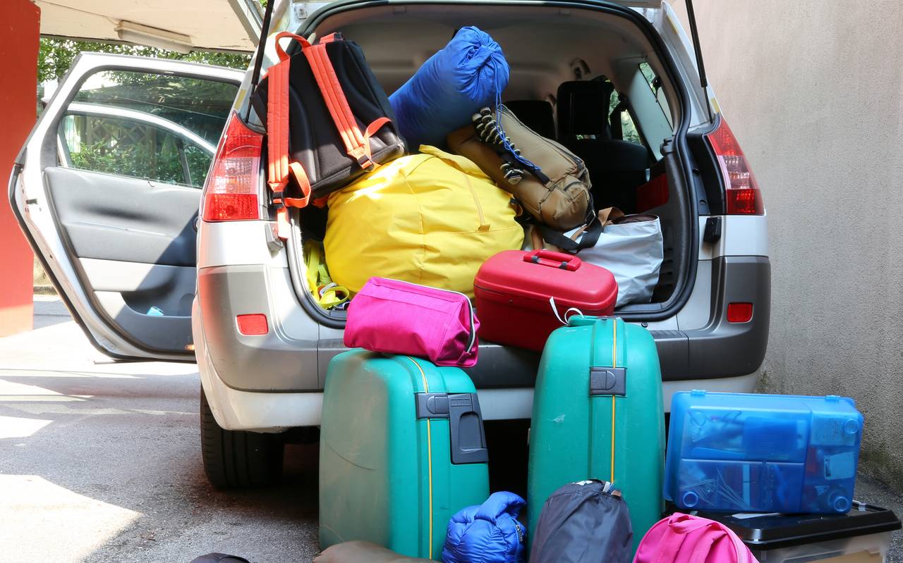 Ein Auto, überladen mit Koffern und Reisetaschen für eine Familienreise.