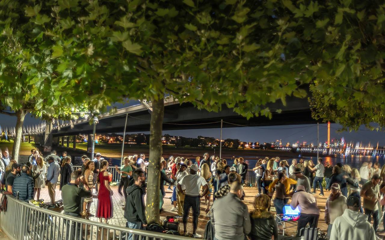 Viele Menschen tanzen in der Nähe der Kniebrücke Salsa unter freiem Himmel. Im Hintergrund sind die Lichter der Rheinkirmes zu sehen.