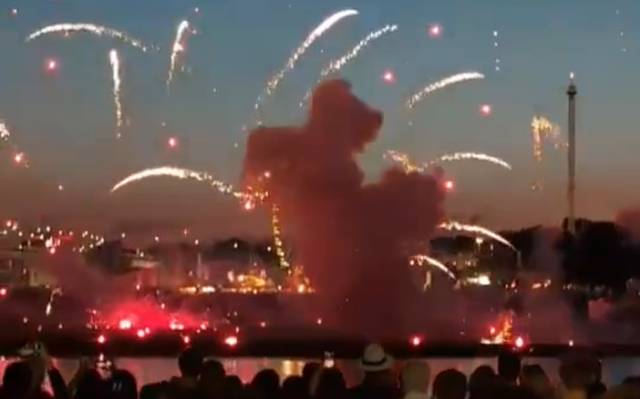 Mehrere Menschen stehen am Mannesmannufer und beobachten das Feuerwerk. Auf der anderen Rheinseite sieht man, wie ein Feuerwerkskörper sehr niedrig explodiert ist.