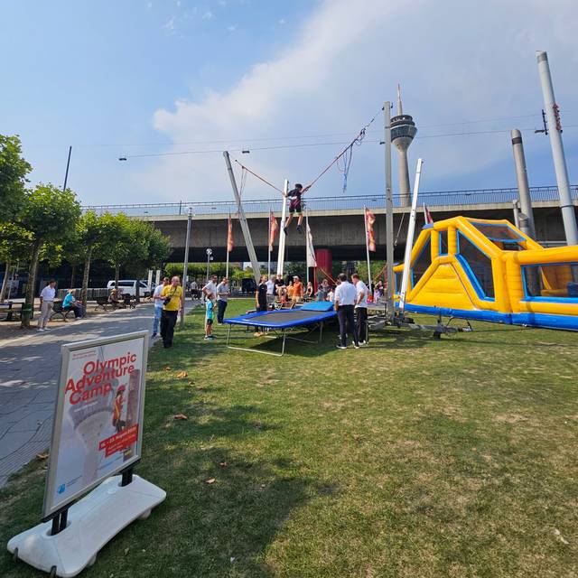 Olympic adventure Camp mit Hüpfburg, Trampolin und Aussicht auf den Rheinturm.