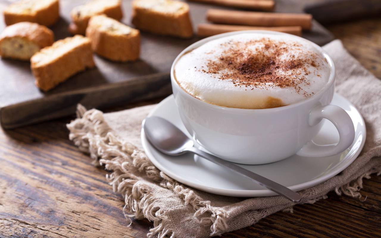 Ein servierter Cappuccino mit Kakao-Pulver. Auch Cantuccini werden serviert.