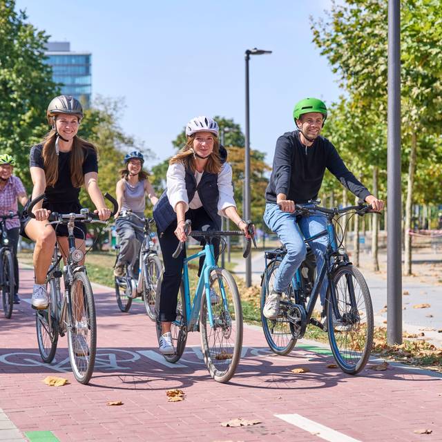 Aufruf zum Mitmachen beim Stadtradeln: Die Landeshauptstadt Düsseldorf beteiligt sich zum zwölften Mal hintereinander am Wettbewerb Stadtradeln des Klima-Bündnisses, dem größten kommunalen Netzwerk für Klimaschutz. Mehrere Fahrradfahrer radeln glücklich über einen Fahrradweg.