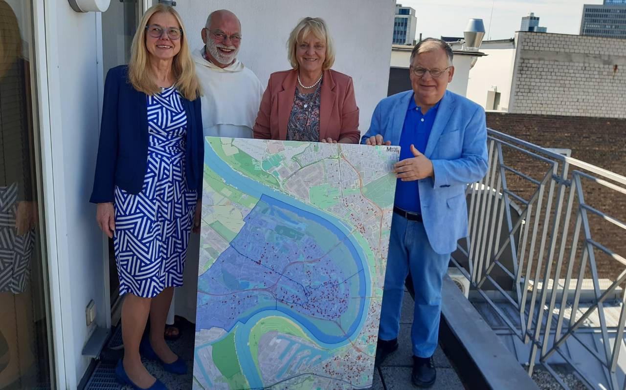 Zwei Frauen und zwei Männer stehen auf einer Dachterrasse, hinter einer Karte von Düsseldorf mit roten Punkten.