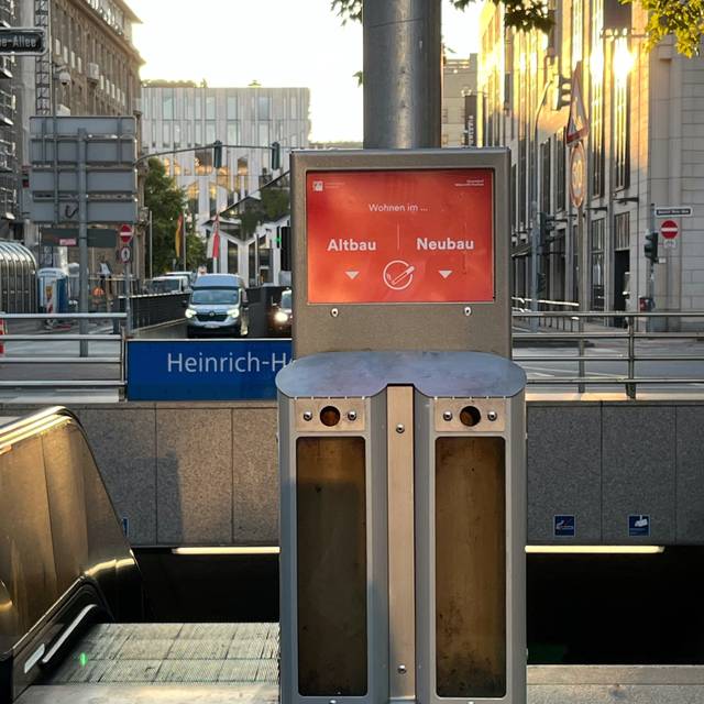 Abstimm-Aschenbecher am Eingang zur U-Bahnstation Heinrich-Heine-Allee. Im Hintergrund Hochhäuser und die Straße in Richtung Könisallee.