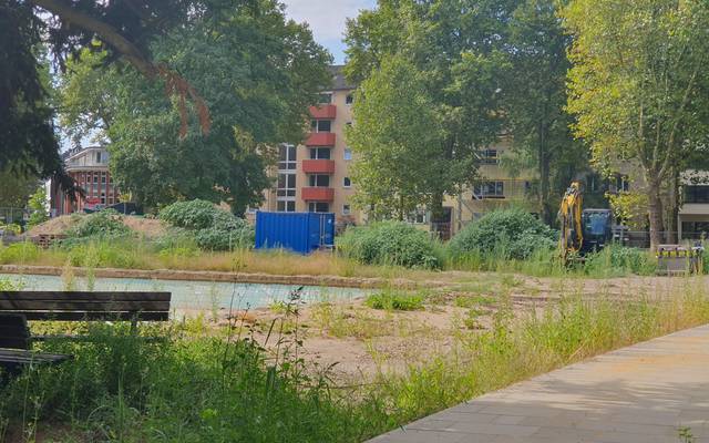 Baustelle auf dem Schillerplatz. Im Hintergrund steht ein gelber Bagger. Der Platz wirkt ungepflegt.