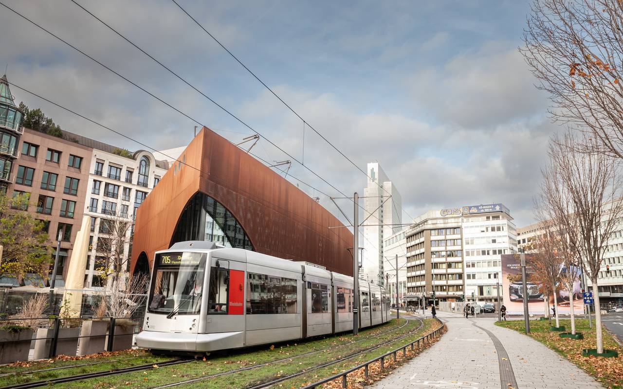Eine Straßenbahn der Düsseldorfer Straßenbahn fährt durch das Stadtzentrum von Düsseldorf. Die Bahn wird von der Rheinbahn betrieben und ist Teil des öffentlichen Nahverkehrs. Im Hintergrund sind städtische Gebäude und Passanten zu sehen.