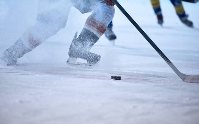 Ein Eishockeyspieler in Aktion. Das Eis spritzt.