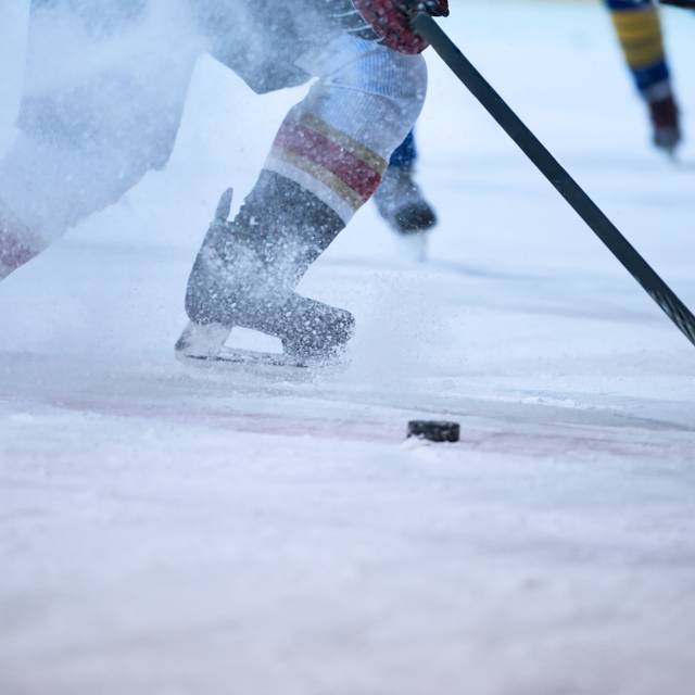 Ein Eishockeyspieler in Aktion. Das Eis spritzt.