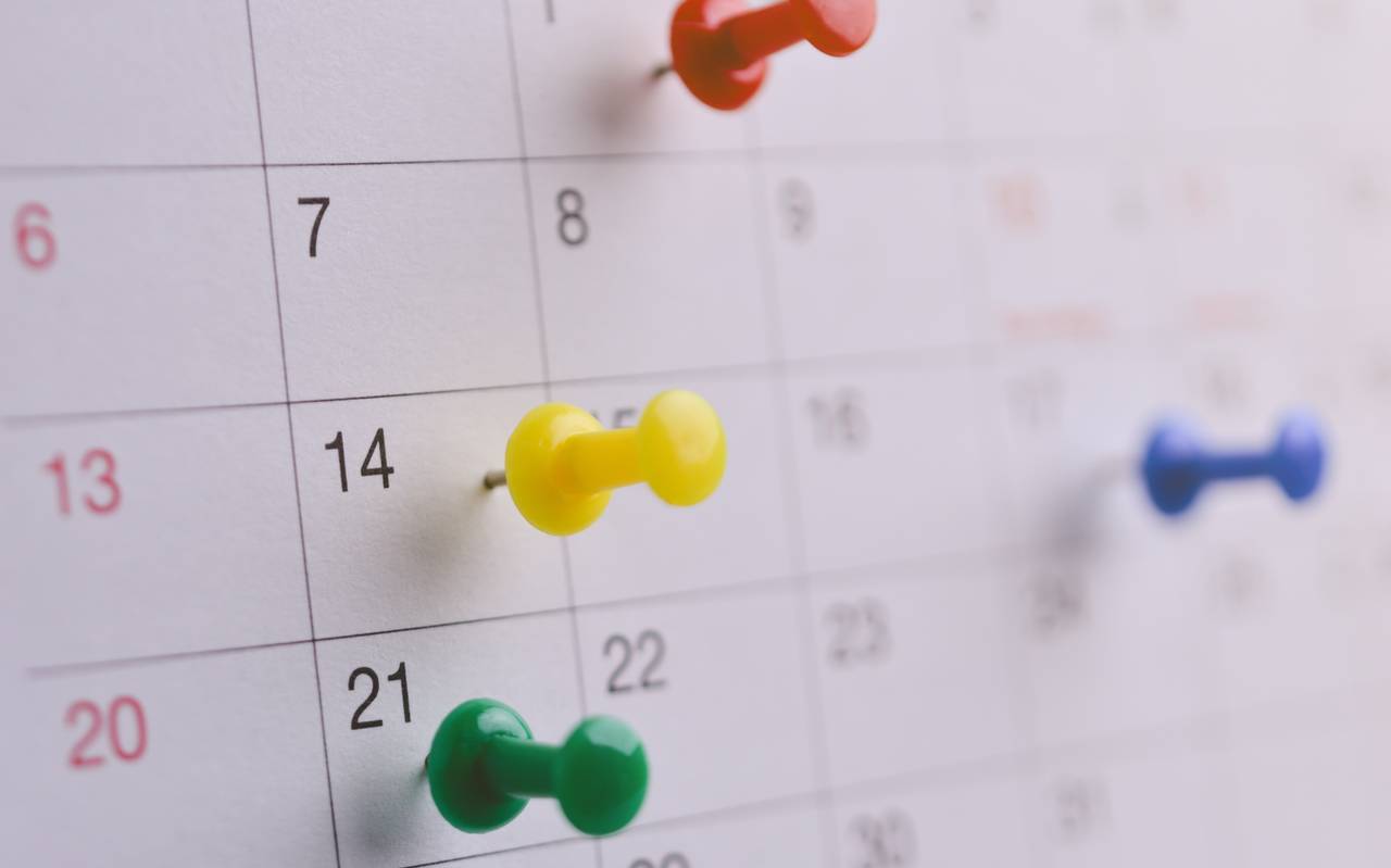 Nahaufnahme eines Steckpins auf einem Kalender, Symbol für Terminvereinbarung, Geschäftsmeeting-Planung oder Reiseplanung.