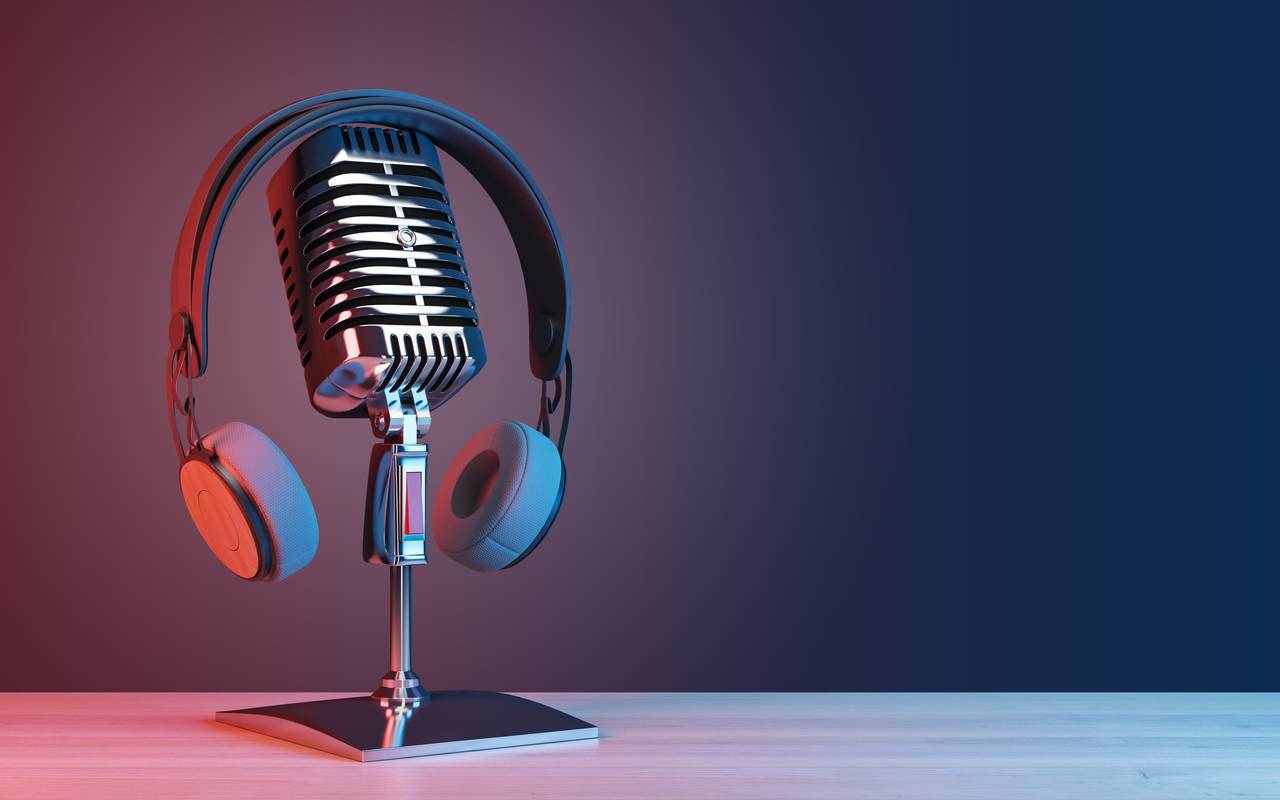 Podcast- und Radiokonzept mit Retro-Mikrofon und Kopfhörern auf leerem Holztisch vor dunkler, leerer Wand.
