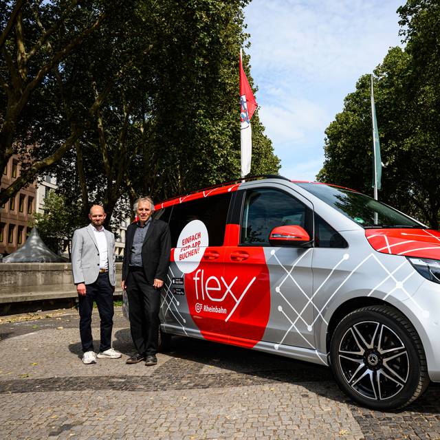 Christian Finke, Bereichsleiter Betrieb der Rheinbahn und  Mobilitäts- und Umweltdezernent Jochen Kral stehen vor einem grauen Flexy-Fahrzeug.