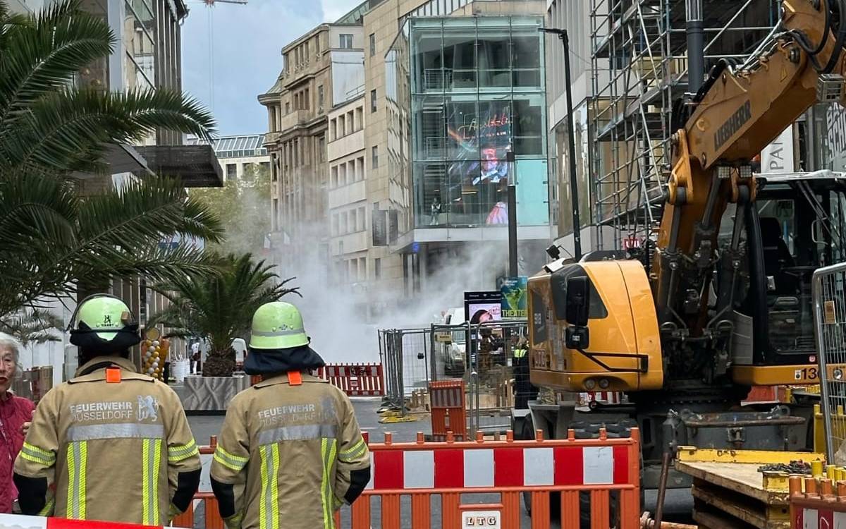 Der Bereich rund um einen Bagger auf der Schadowstraße ist abgesperrt. Feuerwehrleute sind dort im Einsatz. Auf der Straße ist Rauch zu sehen.