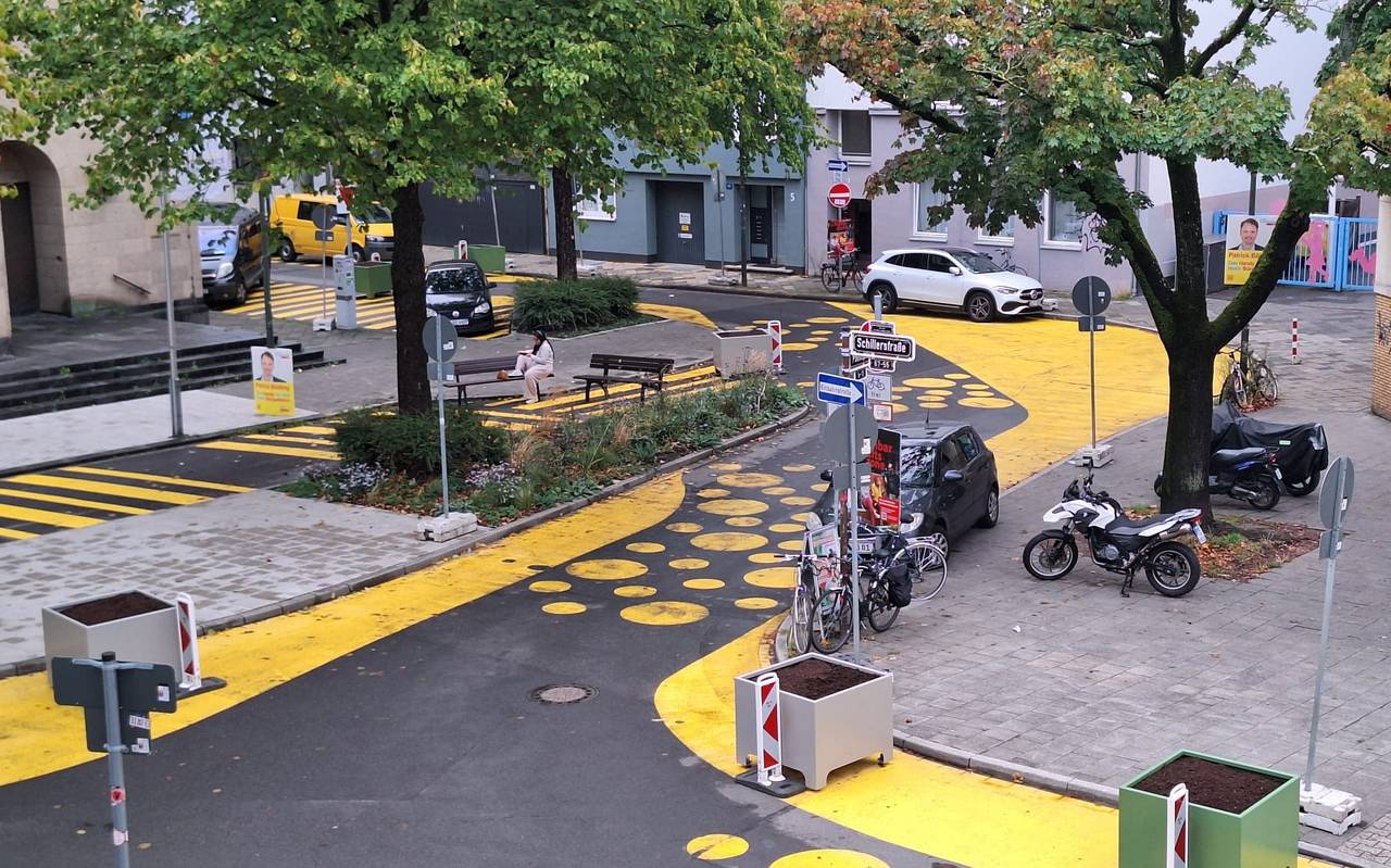 Auf dem Bild sieht man den Paulusplatz mit gelben Streifen und Punkten auf der Straße. Zusätzlich hat die Stadt Blumenkübel und Warnbaken aufgestellt.