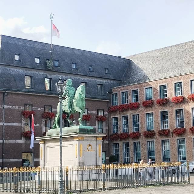 Das Düsseldorfer Rathaus mit bepflanzten Geranienkästen in der Altstadt. Davor steht die Statue von Jan Wellem.