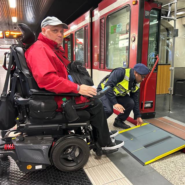 Ein Mann im Rollstuhl kann über eine mobile Rampe am Bahnsteig bequem in die U-Bahn einsteigen.