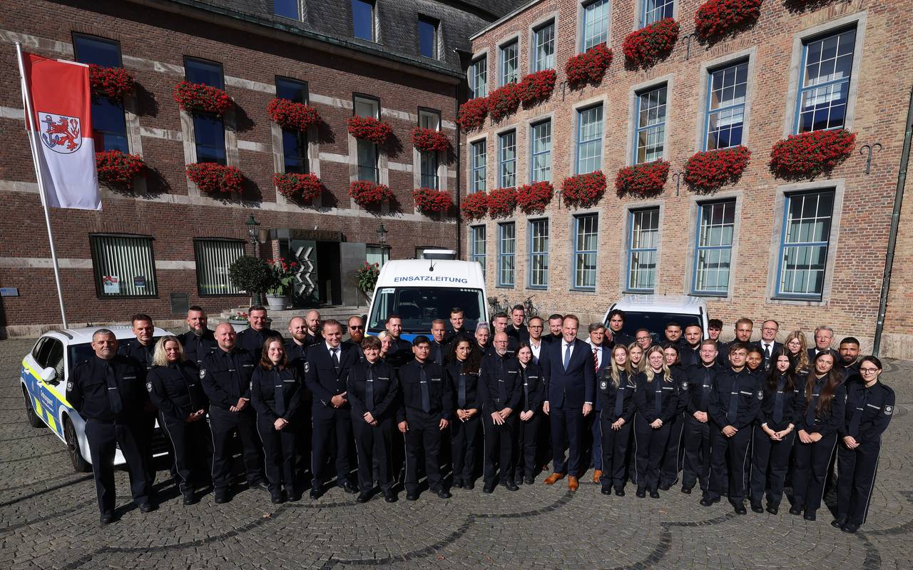 Über 50 neue OSD-Mitarbeitende stehen aufgereiht vor dem Düsseldorfer Rathaus. Hinter der Gruppe parken Autos des OSD. Vor dem Rathaus weht die Düsseldorf-Flagge.