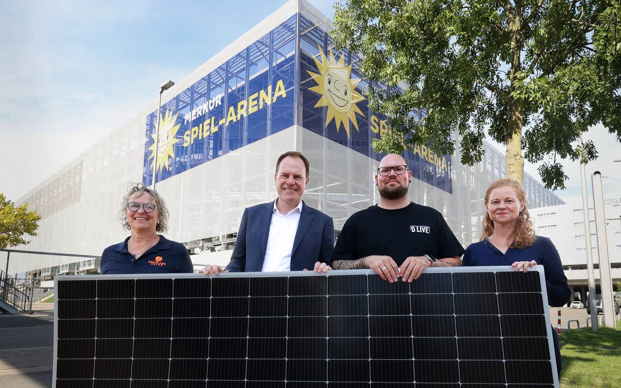 Oberbürgermeister Stephan Keller hält mit Verantwortlichen von D.LIVE ein Solar-Panel.
