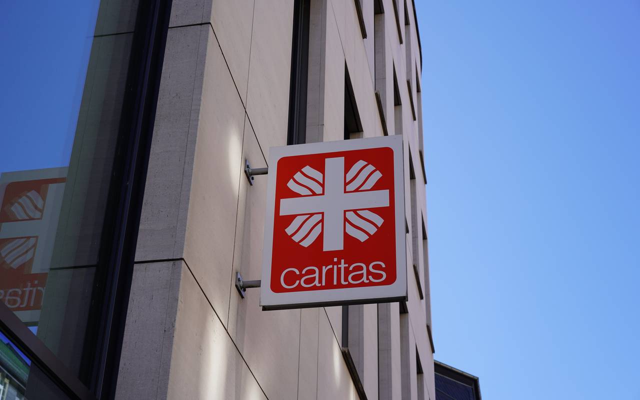 Ein Schild der Caritas hängt an einer Häuserwand. Dieses Bild dient als Symbolbild für die Caritas.