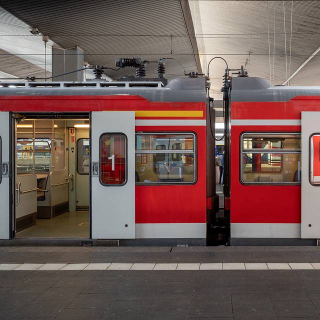 Eine S-Bahn hält am Bahnsteig eines Bahnhofs in Düsseldorf, Deutschland, und die automatischen Türen öffnen sich.