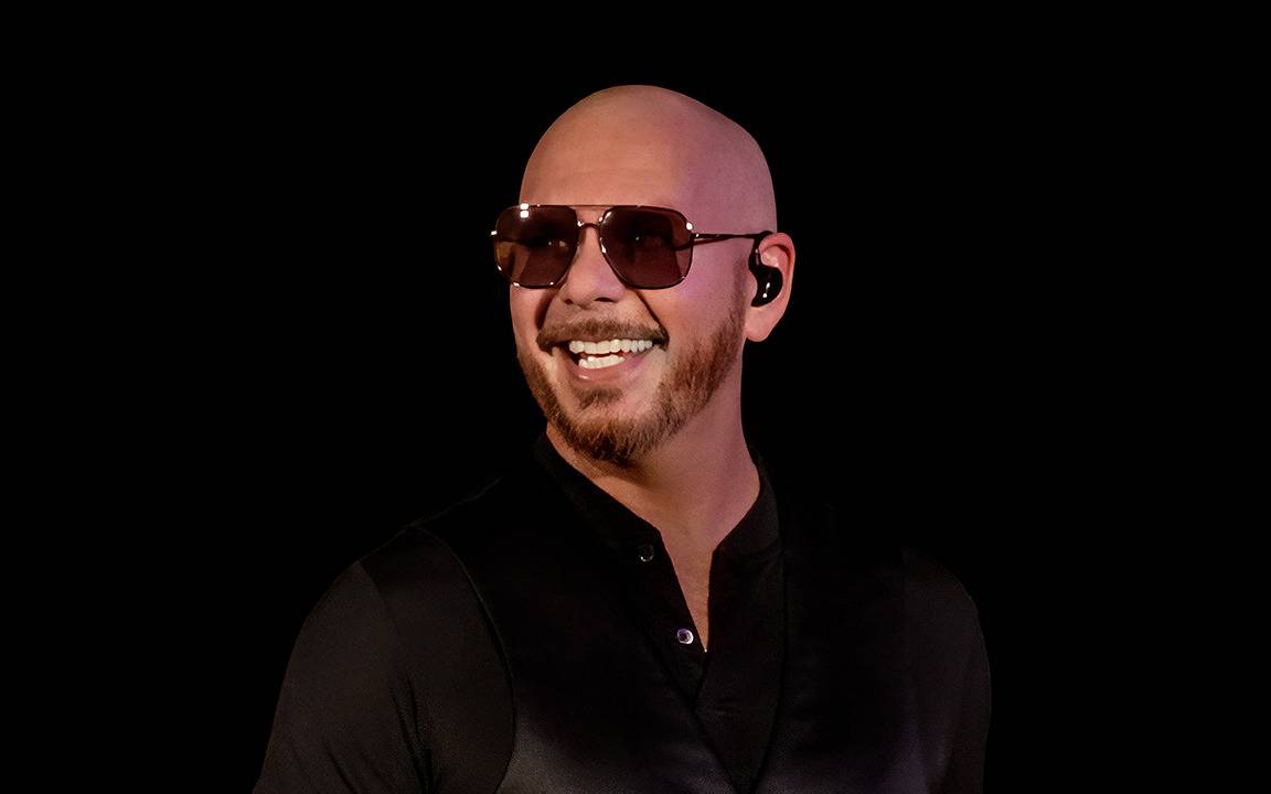 Der Künstler Pitbull steht vor einem schwarzen Hintergrund.