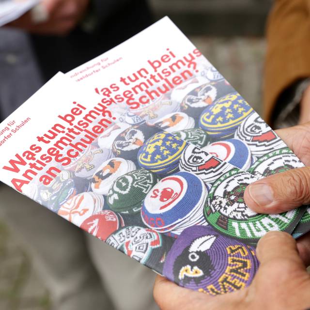 Zwei Hände halten zwei Exemplare der Broschüre "Was tun bei Antisemitismus?" in die Kamera