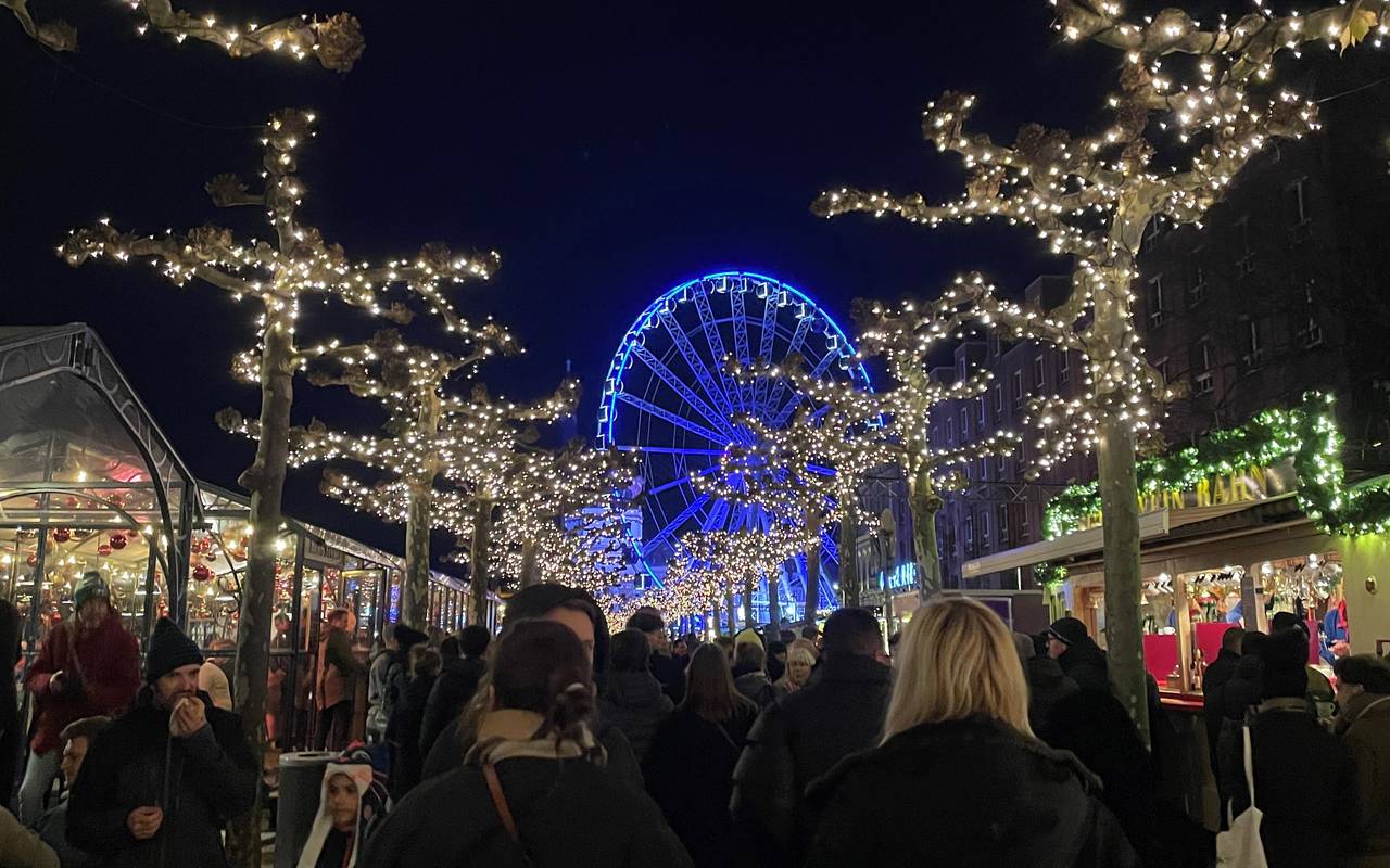 Menschen schlendern über den Roncalli-Weihnachtsmarkt in Düsseldorf. Im Hintergrund ist ein Riesenrad zu sehen.