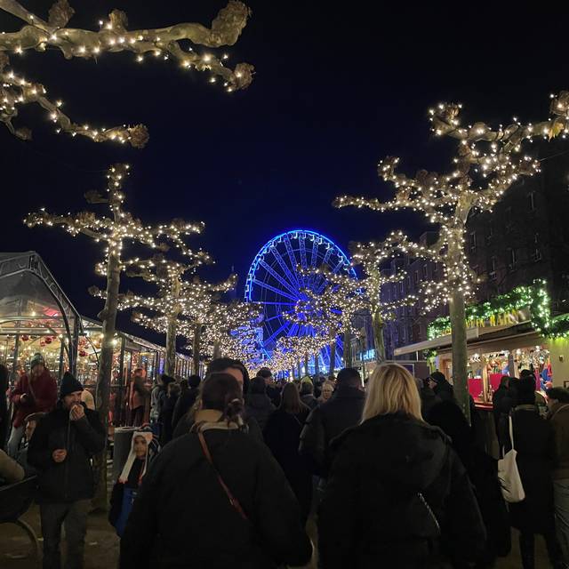 Menschen schlendern über den Roncalli-Weihnachtsmarkt in Düsseldorf. Im Hintergrund ist ein Riesenrad zu sehen.