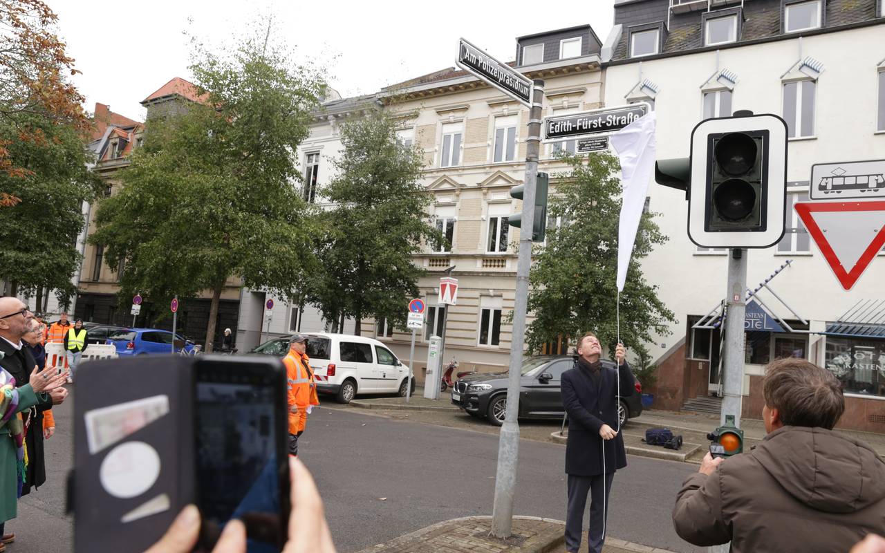OB Keller enthüllt die neuen Straßenschilder "Am Polizeipräsidium" und "Edith-Fürst-Straße". Viele Nachbarn und Fotografen beobachten die Aktion auf dem ehemaligen Jürgensplatz.