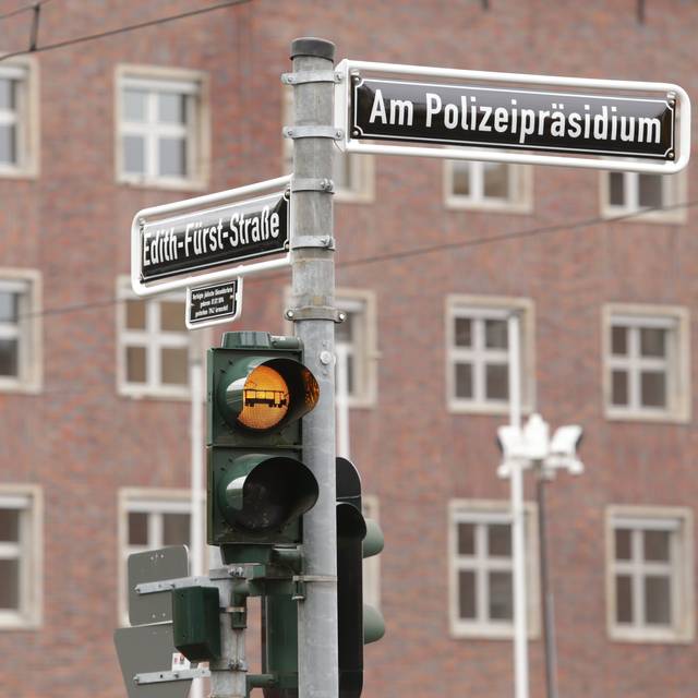 Vor dem Polizeipräsidium steht ein Ampelmast, der auf eine Straßenbahn hinweist. An dem Mast auf dem ehemaligen Jürgensplatz hängen außerdem die neuen Straßenschilder "Am Polizeipräsidium" und "Edith-Fürst-Straße"