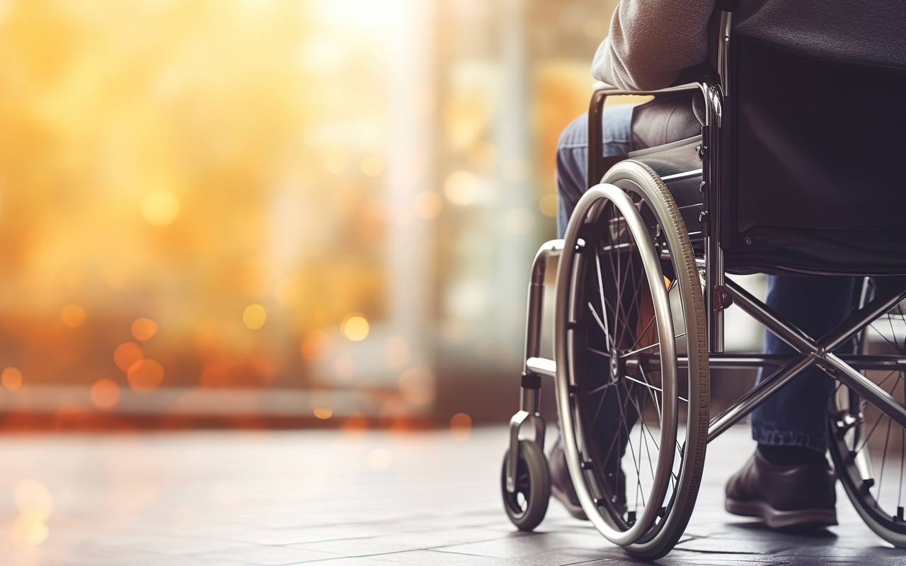 Mann im Rollstuhl mit körperlicher Behinderung, Nahaufnahme, freier Hintergrund.