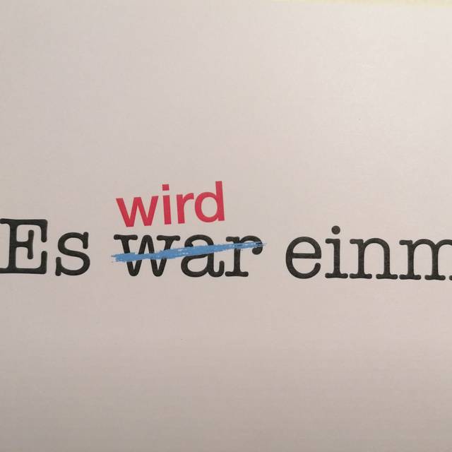 Schwarzer Schriftzug auf weißem Papier: "Es war einmal" - das "war" ist durchgestrichen. Darüber steht in roter Schrift "wird".